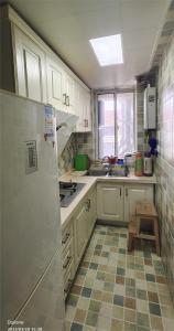 南京雅伦之屋 Yailon Aparment的厨房配有白色橱柜和 ⁇ 格地板