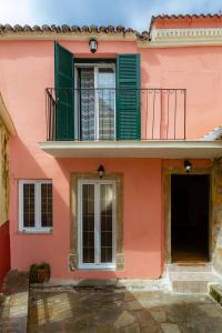 圣马太奥斯Vitos Village House的粉红色的建筑,设有绿色窗户和阳台