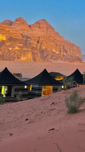 瓦迪拉姆MARS LUXURY CAMP WADi RUM的沙漠中的一座建筑,以群山为背景