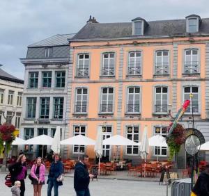 蒙斯Le Vieux Cèdre Grand Place的一群人走在一座大建筑前面