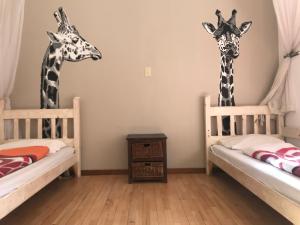 温特和克ParadiseGarden Backpackers的两张长颈鹿站在带两张床的房间