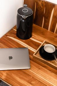 乌布Happiness Apartments Bali Ubud的一张带咖啡壶的木桌上的笔记本电脑