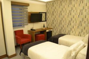 卡特佩RİVADA HOTEL的酒店客房设有两张床、一张桌子和一台电视。