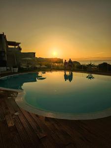 特罗佩阿Residence New Paradise的一个空的游泳池,在后面有日落