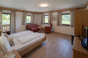 HintergöriachLandhotel - Apartments Bauer的一间卧室配有一张床、一把椅子和电视