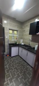 AgegeHEN - CAP SERVICED APARTMETS的厨房配有白色橱柜和黑色台面