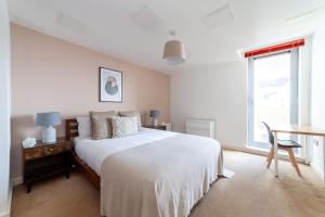 伦敦The Stratford Apartment的一间卧室配有一张床、一张书桌和一个窗户。