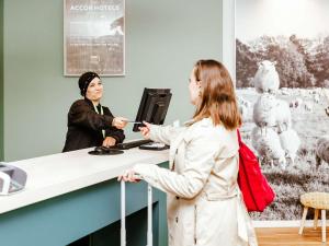 卢森堡卢森堡中心火车站宜必思尚品酒店的站在柜台与顾客交谈的女人