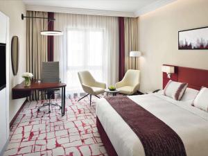 迪拜Mövenpick Hotel & Apartments Bur Dubai的酒店客房,配有一张床、一张桌子和椅子