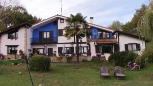 ElosuAgroturismo Atxarmin的白色和蓝色的房子,前面有椅子