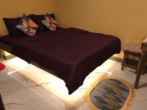爱妮岛Elmo’s place的一张带深紫色毯子和枕头的床