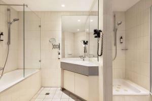 卡斯特罗普-劳克塞尔Vienna House Easy by Wyndham Castrop-Rauxel的白色的浴室设有水槽和淋浴。