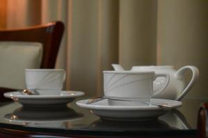 文尼察Hotel Feride的桌子上放两个白杯和碟子