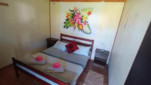 安加罗阿Camping Hostal Tipanie Moana Aeropuerto Centro的一间小卧室,配有一张床和墙上的绘画