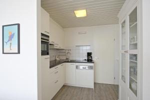 栋堡Residence de L'Europe - Baddomburg的厨房配有白色橱柜和天花板