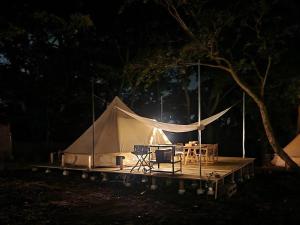 真鹤町COUSCOUS Glamping Manazuru的木制甲板上的帐篷,配有桌椅