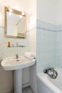 圣拉斐尔Lagrange Vacances Le Domaine des Grands Pins的浴室配有盥洗盆、镜子和浴缸