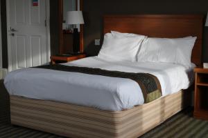 曼彻斯特Fairway Inn的一张大床,带有木制床头板,位于酒店客房内