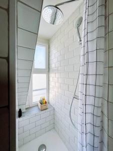 巴黎Jolie studio Parisien的带淋浴的白色浴室和窗户。