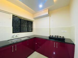 KazhakuttamAL-Kabeer Heights的厨房配有红色橱柜、水槽和窗户