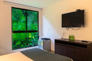 圣罗莎德卡瓦尔Termales Santa Rosa De Cabal的卧室设有大窗户和平面电视。
