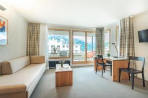 圣莫里茨Hauser Hotel St. Moritz的客厅配有沙发和带书桌的桌子