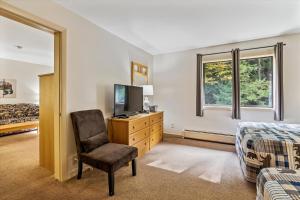 基灵顿Cedarbrook Deluxe one bedroom suite with outdoor heated pool 21416的一间卧室配有一张床、一把椅子和电视