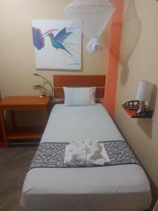 伊基托斯Amazon House Hostel的一张位于小房间的床,配有白色床单