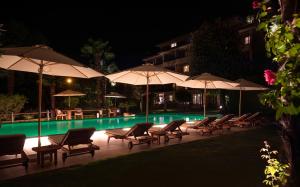 洛迦诺Boutique-HOTEL REMORINO, a Private Selection Hotel的游泳池在晚上提供椅子和遮阳伞