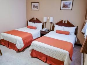 危地马拉皇宫酒店的酒店客房带两张床,带橙色和白色的床单。