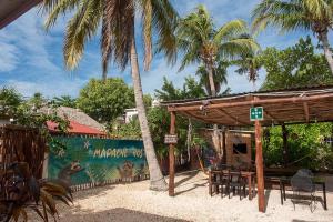 奥尔沃克斯岛Mapache Hostel & Camping的一个带桌椅和棕榈树的凉亭