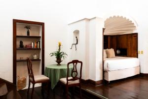 迪坡斯特兰Posada del Tepozteco - Hotel & Gallery的卧室配有一张床和一张桌子及椅子