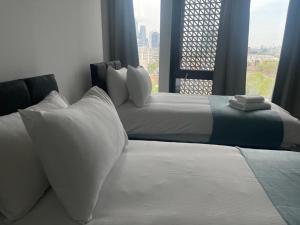 伦敦Manhattan Pad by condokeeper的带窗户的客房内的两张床和白色枕头