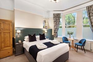哈罗盖特Fountains Guest House - Harrogate Stays的一间卧室配有一张大床和一张桌子及椅子