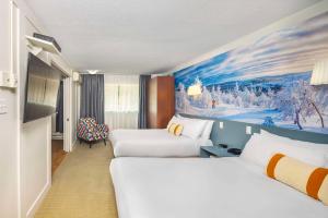 拉马巴耶Clarion Pointe La Malbaie的酒店客房设有两张床,墙上挂有绘画作品
