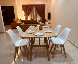 居銮Kluang 4 bedrooms 4 bathrooms的客厅配有一张带白色椅子的木桌