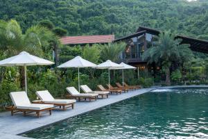 宁平Tam Coc Retreat Ninh Binh的毗邻度假酒店的带躺椅和遮阳伞的游泳池