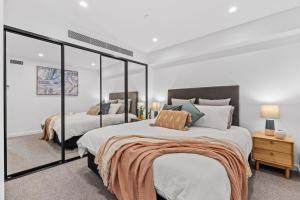 霍巴特Designer Apartment - giant terrace - city location的一间卧室设有两张床和大镜子