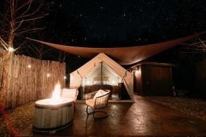布兰森Cozy Unique Glamping on 53 acres - Bedrock Site的帐篷在晚上前配有桌椅