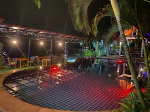 功孟海滩Krabi Villa Phu Khao Private Resort的一个带桌子和棕榈树的夜间游泳池