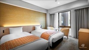 松山松山大和鲁内酒店的酒店客房设有两张床和窗户。