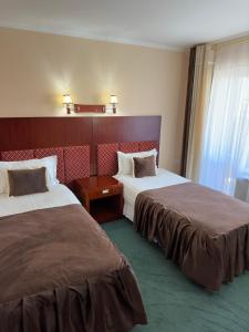 布哈拉Inturist Hotel Classic Grand Bukhara的酒店客房设有两张床和窗户。