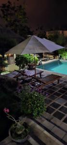 努沙杜瓦安靖别墅酒店的一张野餐桌和一把遮阳伞,位于游泳池旁