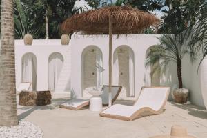坎古MAJA Canggu的一个带椅子和遮阳伞的庭院,棕榈树