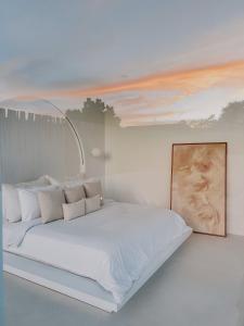 坎古MAJA Canggu的卧室配有一张白色床,墙上挂有绘画作品