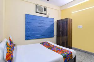 加尔各答FabHotel Sapphire Comfort的卧室配有一张床,墙上挂有绘画作品