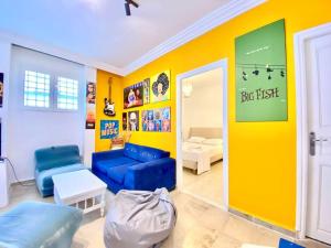 拉马萨S+1 au cœur de la Marsa plage的客厅设有蓝色的沙发和黄色的墙壁
