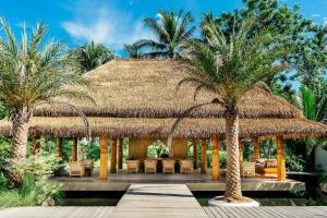 波普托Zazen Boutique Resort & Spa - SHA Plus的拥有茅草屋顶和棕榈树的度假酒店