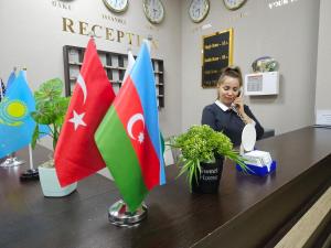 巴库Cityland Hotel Baku的一位女士在带有旗帜的房间里用手机说话