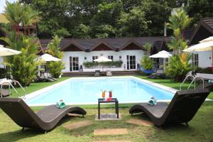 科隆Sunz en Coron Resort的一个带两把椅子的游泳池以及一座房子
